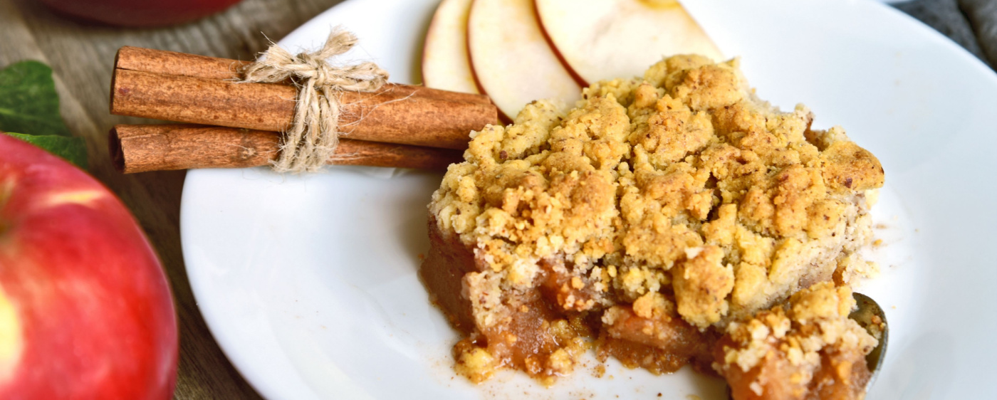 Apple crisp on plate with a cinnamon stick.