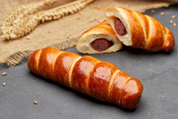 rolled hot dog sausages in the dough baked in puff pastry on dark background - pretzel hot dog stock pictures, royalty-free photos & images