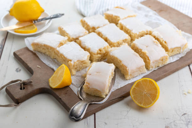 vegan lemon cake from the sheet with icing sugar glaze - glazed lemon cake stock pictures, royalty-free photos & images