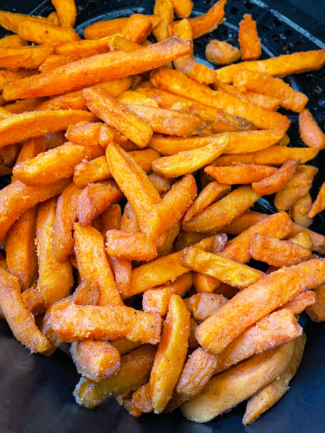 close-up image of golden brown, fresh sweet potato french fries cooked in air fryer, healthier alternative to snack cooking, elevated view - sweet potato fries stock pictures, royalty-free photos & images