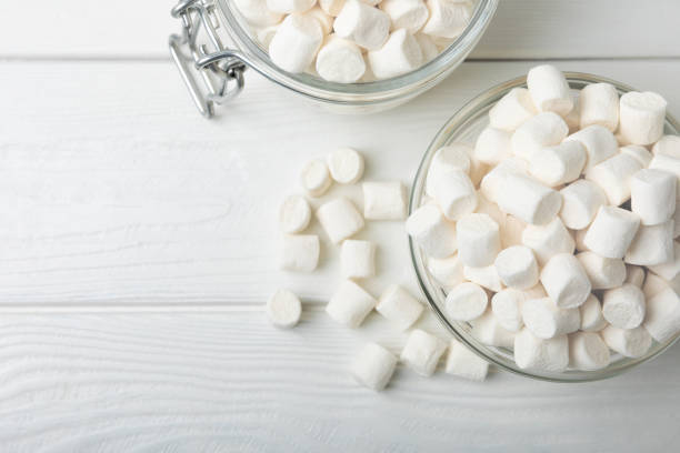 loose white marshmallows on white texture wood.sweets and snacks for a snack.chewy candy close-up.copy space.place for text. - marshmallows stock pictures, royalty-free photos & images