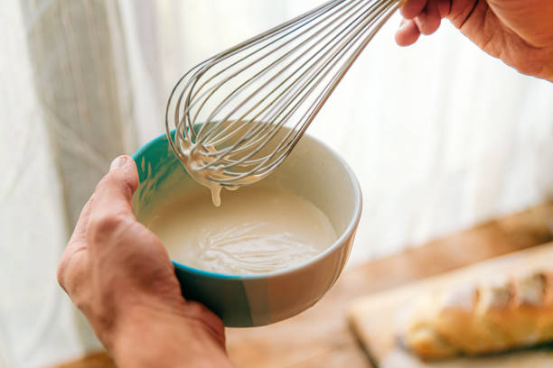 cropped photo of men's hands while cooking white cream sauce with a whisk. mayonnaise, bechamel - making sauce stock pictures, royalty-free photos & images