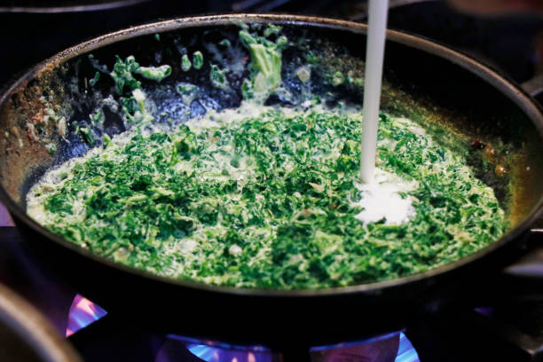 creamy baby spinach in a cooking pan on fire - creamed spinach stock pictures, royalty-free photos & images