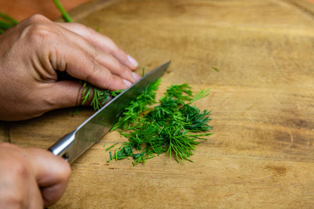 woman cutting green dill on the cutting board - chopped dill stock pictures, royalty-free photos & images