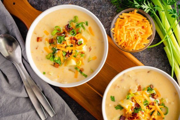 bowls of loaded baked potato soup topped with sour cream, cheddar cheese, bacon, and chives - potato cheddar soup stock pictures, royalty-free photos & images