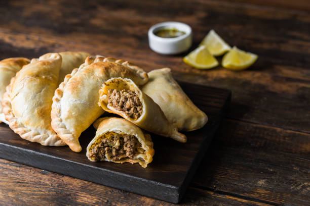 traditional baked argentine empanadas savoury pastries with meat beef stuffing against wooden background - beef empanadas stock pictures, royalty-free photos & images