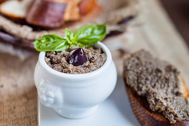 black tapenade in bowl, crostini with olive paste - olive tapenade stock pictures, royalty-free photos & images