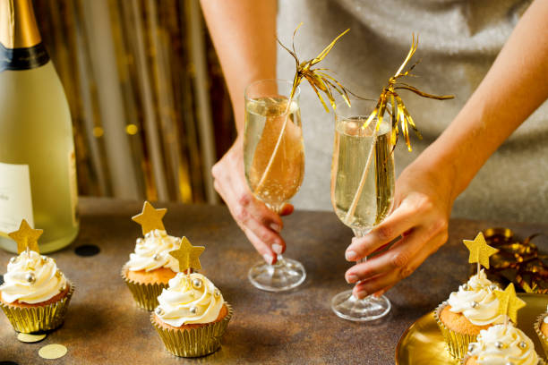 close-up of woman serving champagne and cupcakes for new years eve party - champagne cupcake stock pictures, royalty-free photos & images