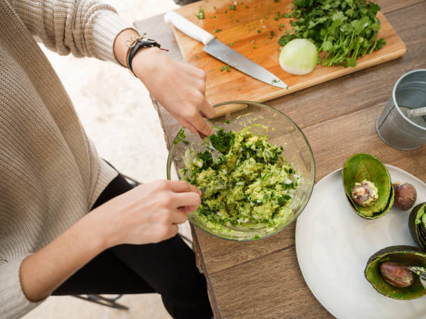 young woman making guacamole - making guacamole stock pictures, royalty-free photos & images