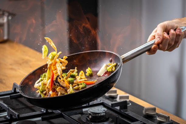 chef tossing flaming vegetable - cooking drunken noodles stock pictures, royalty-free photos & images