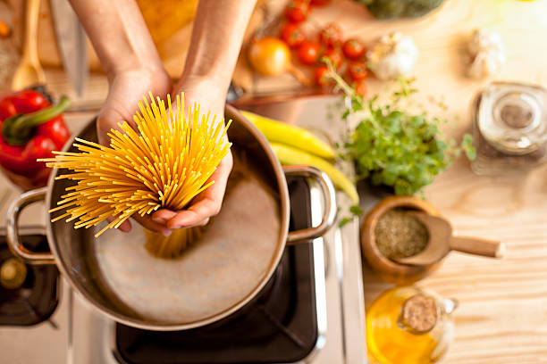 woman in the kitchen holding spaghetti - one pot spaghetti stock pictures, royalty-free photos & images