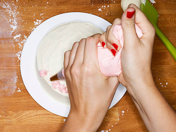 female decorating a cake - cake decorating stock pictures, royalty-free photos & images