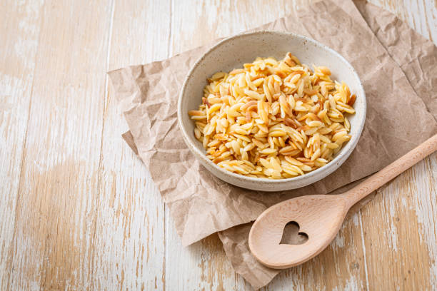 cooked italian pasta, risoni, orzo in a bowl on wooden table - cooking orzo stock pictures, royalty-free photos & images